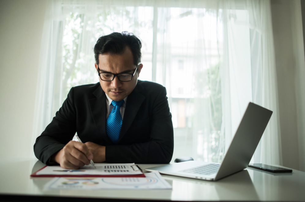 Young businessman working on a laptop at an office, representing the new compliance strategies by the LHDNM Strategy Compliance Department to ensure transparency and enforce tax regulations in Malaysia